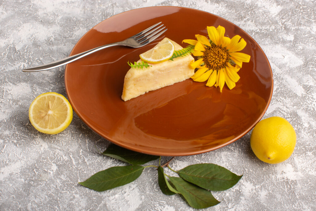 front view delicious cake slice with lemon inside brown plate light surface