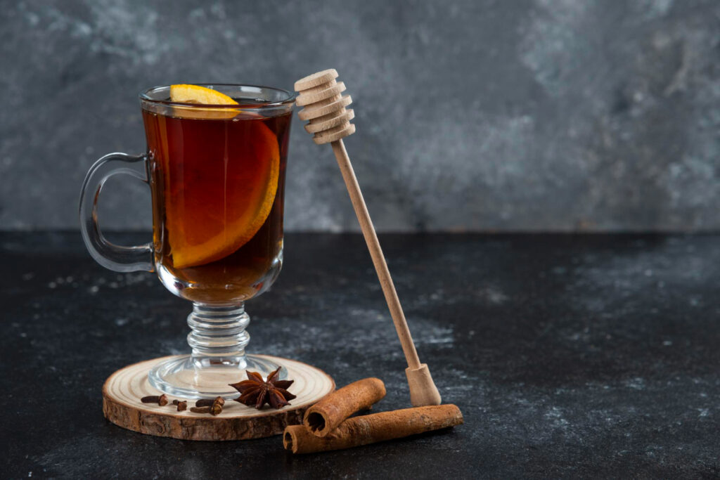 glass cup tea with cinnamon sticks wooden dipper