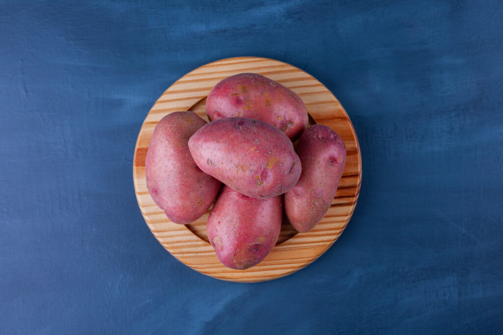wooden plate ripe sweet potatoes blue surface